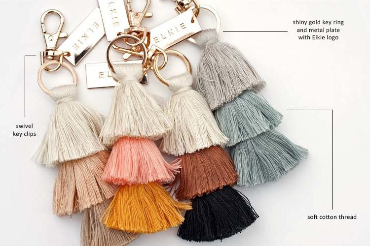 inforgraphic of four tassle bag charms with gold plates that say elkie. Mocha Sherbet Sand Fawn Cedar The Blues
