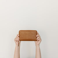 hands holding up elkie saddle wallet with white background 