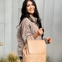 Woman smiling while holding the Tan Milan diaper back by grab handle