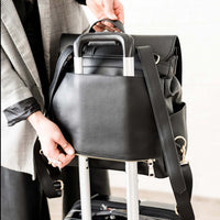 Elkie Co Milan Ebony backpack being put over suitcase through luggage pocket