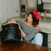 Woman sitting in kitchen opening Ebony Capri backpack