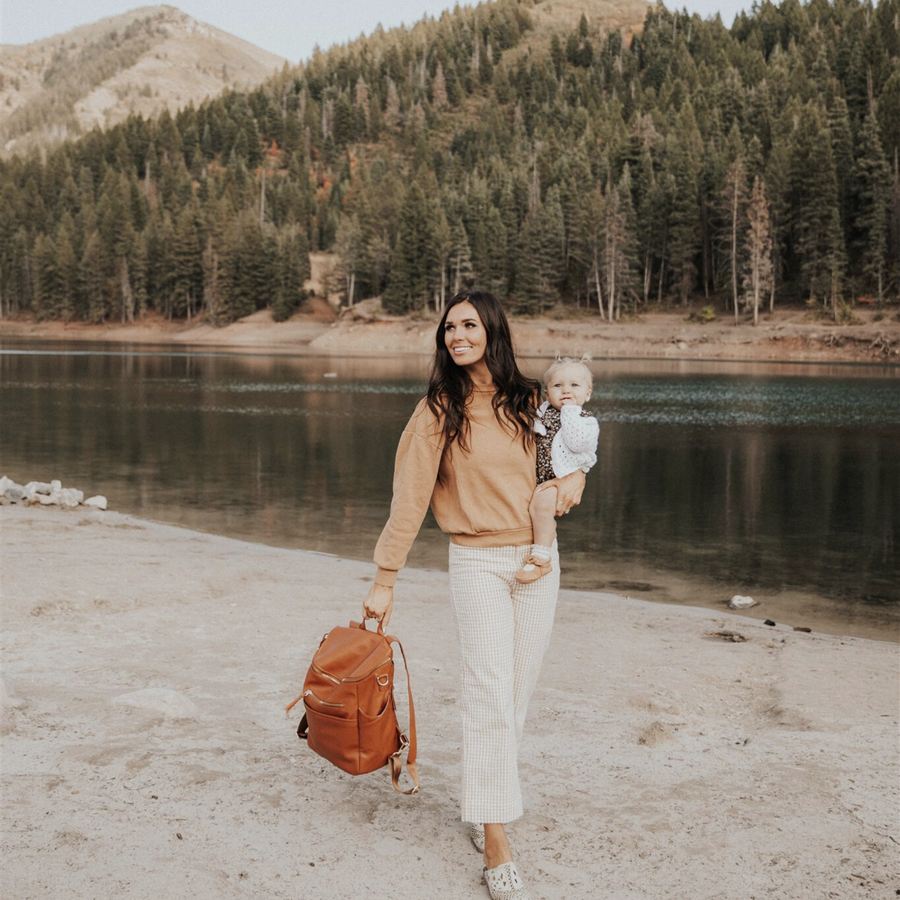 wearing walking by lake holding the Saddle capri backpack by the grab handle