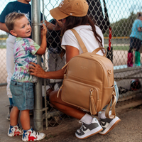 Mom at baseball game wearing the Tan aspen midi backpack